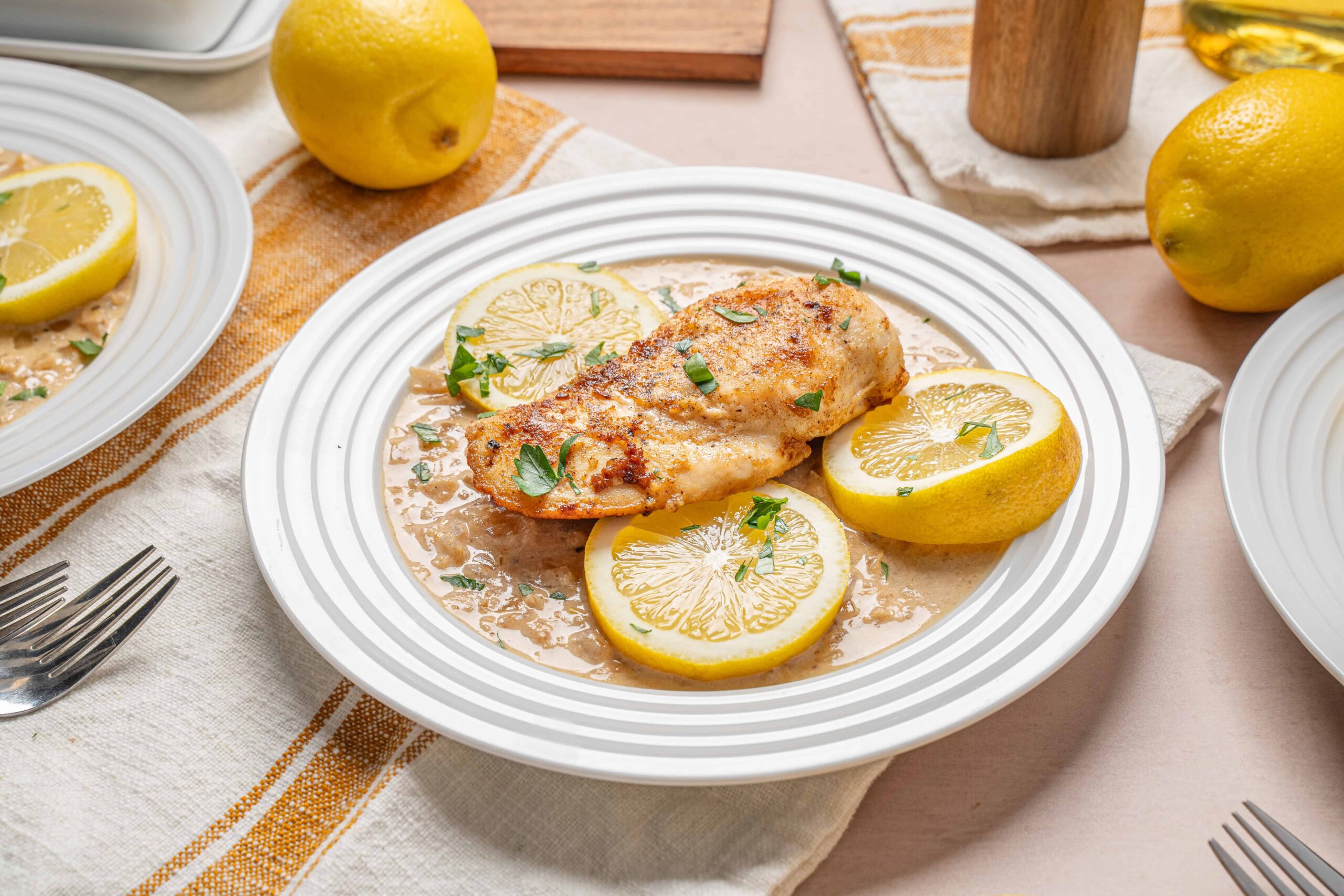 Juicy lemon grilled chicken breast served with lemon slices and fresh herbs on a white plate, perfect for healthy dinner recipes and citrus-flavored poultry dishes.
