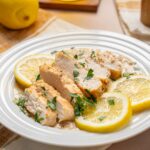 Juicy lemon herb chicken breast garnished with fresh parsley, served on a white plate with lemon slices for a flavorful, healthy meal.