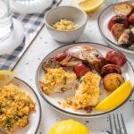 Golden baked fish fillets with crispy breadcrumb topping served with roasted new potatoes and grilled vegetables, garnished with lemon wedges for a delicious healthy seafood meal.