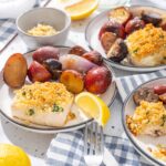 Roasted chicken breast with crispy crumbs served with roasted red potatoes and fresh lemon wedges on a white plate. Delicious meal perfect for family dinners and comfort food cravings.