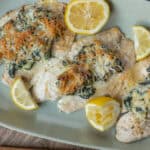 Baked chicken breasts topped with spinach, shredded carrots, and melted cheese served with lemon wedges for a nutritious and flavorful meal. Perfect for easy weeknight dinners or healthy family dishes.