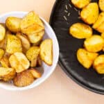 Crunchy roasted garlic potatoes served in a white bowl and black platter, perfect for comfort food and side dishes. Delicious golden-brown potatoes seasoned and roasted to perfection.