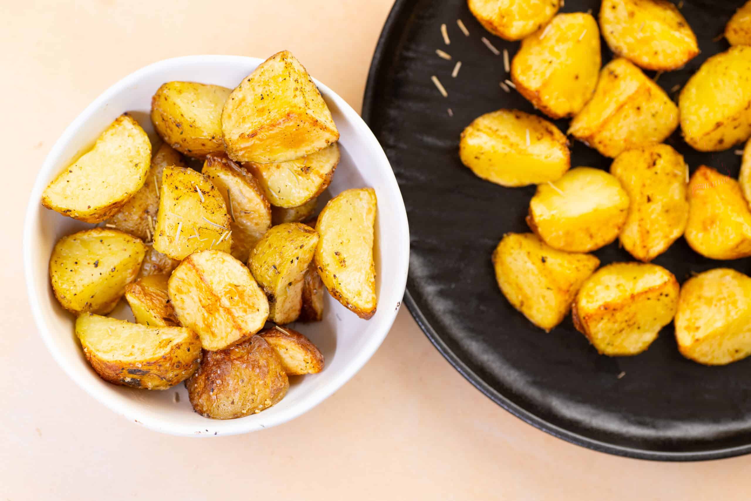 Crunchy roasted garlic potatoes served in a white bowl and black platter, perfect for comfort food and side dishes. Delicious golden-brown potatoes seasoned and roasted to perfection.
