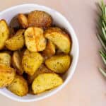 Crispy roasted potato wedges with herbs in a white bowl, served as a delicious side dish or snack. Perfect for breakfast, lunch, or dinner, seasoned with spices and herbs for flavor.
