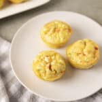 Fluffy savory egg muffins with colorful vegetables on a white plate, healthy breakfast idea.