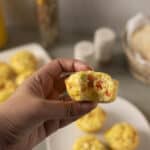 Crispy breakfast egg muffins with vegetables and cheese, close-up of hand holding a muffin with a bite taken out, healthy homemade egg muffins recipe for breakfast or brunch.