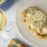 Butter chicken casserole with melted cheese and fresh herbs served on a white plate, glass of white wine, colorful napkin, culinary dish, comfort food, easy dinner recipe, cheesy baked chicken, homemade chicken casserole, hearty chicken dish, savory comfort food.