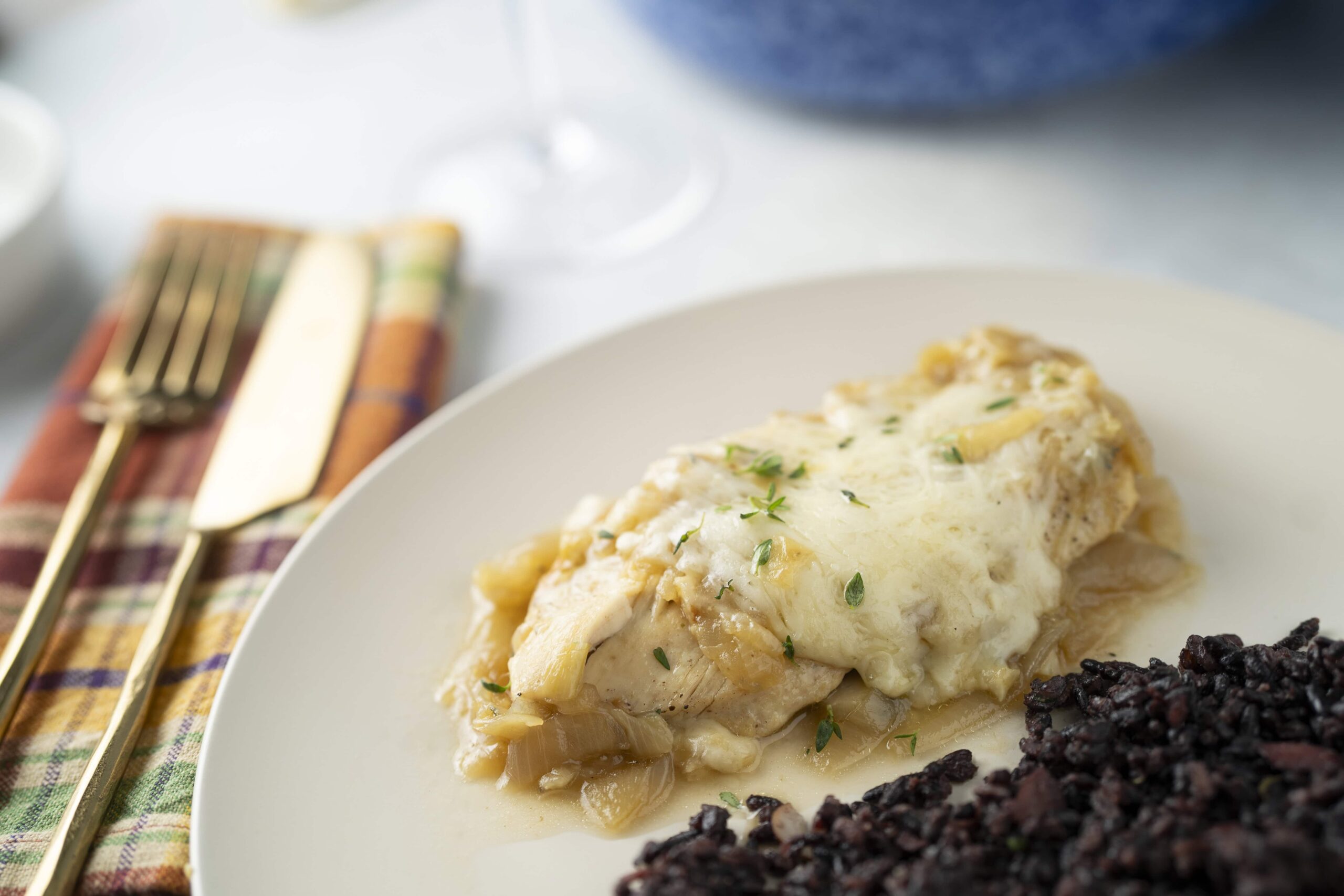 Creamy chicken pot pie with sautéed onions and herbs served with a side of wild rice on a white plate. Perfect comfort food recipe, ideal for family dinners and easy to prepare at home.