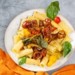 Roasted cherry tomato pasta with fresh basil and mushrooms on white plate, served with colorful cherry tomatoes and basil leaves for authentic Italian flavor.