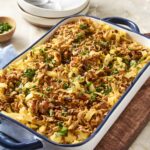 Savory ground beef and pasta casserole with melted cheese and fresh herbs in a blue and white baking dish, served as a comforting home-cooked meal, top view.
