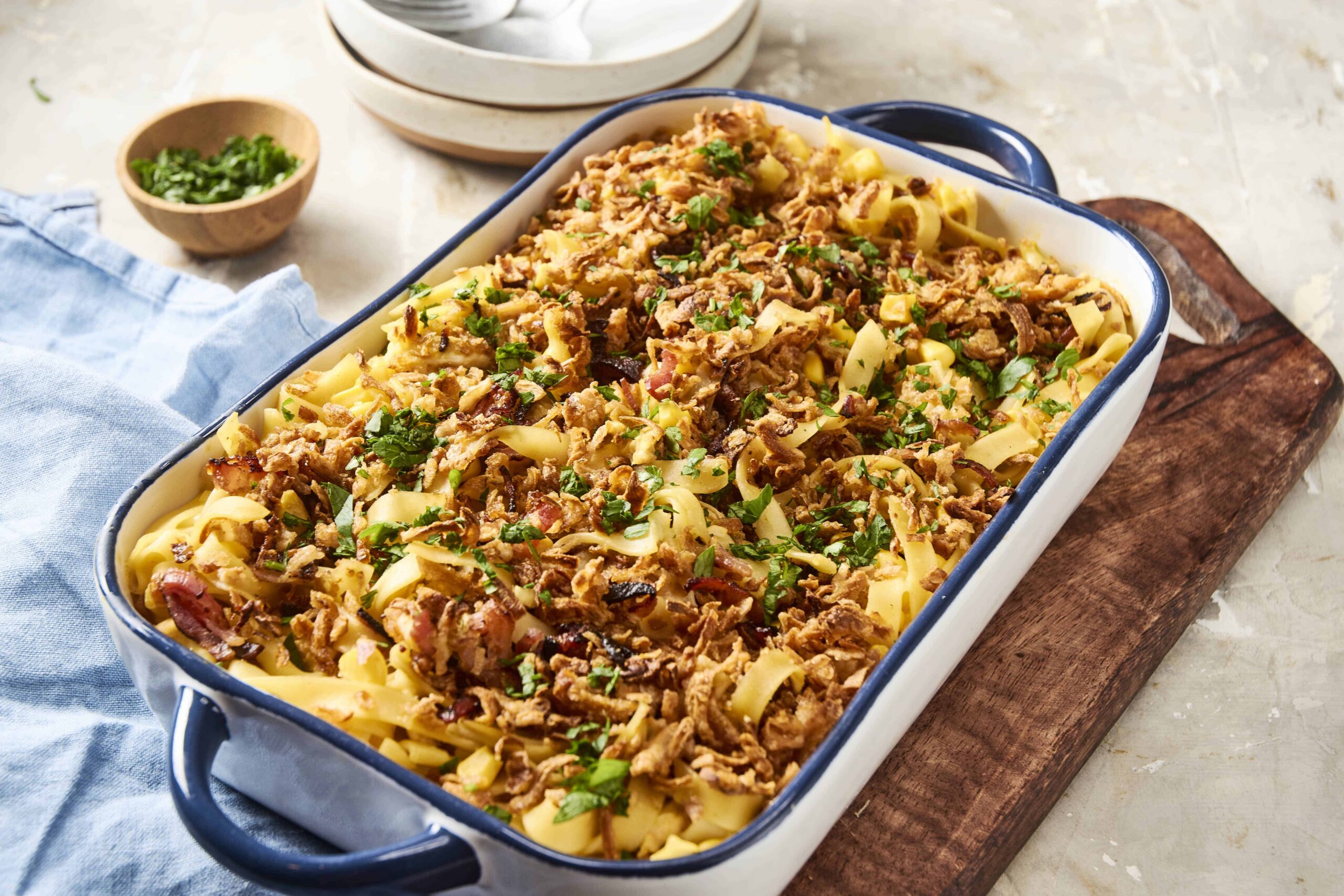 Savory ground beef and pasta casserole with melted cheese and fresh herbs in a blue and white baking dish, served as a comforting home-cooked meal, top view.