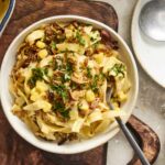 Creamy pasta casserole with bacon, corn, and fresh herbs in a white bowl, served with a spoon; a delicious comfort food recipe from Hey Recipe.