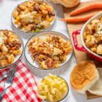 Creamy baked pasta casserole with ground beef, cheese, and vegetables served with dinner rolls on a rustic table.
