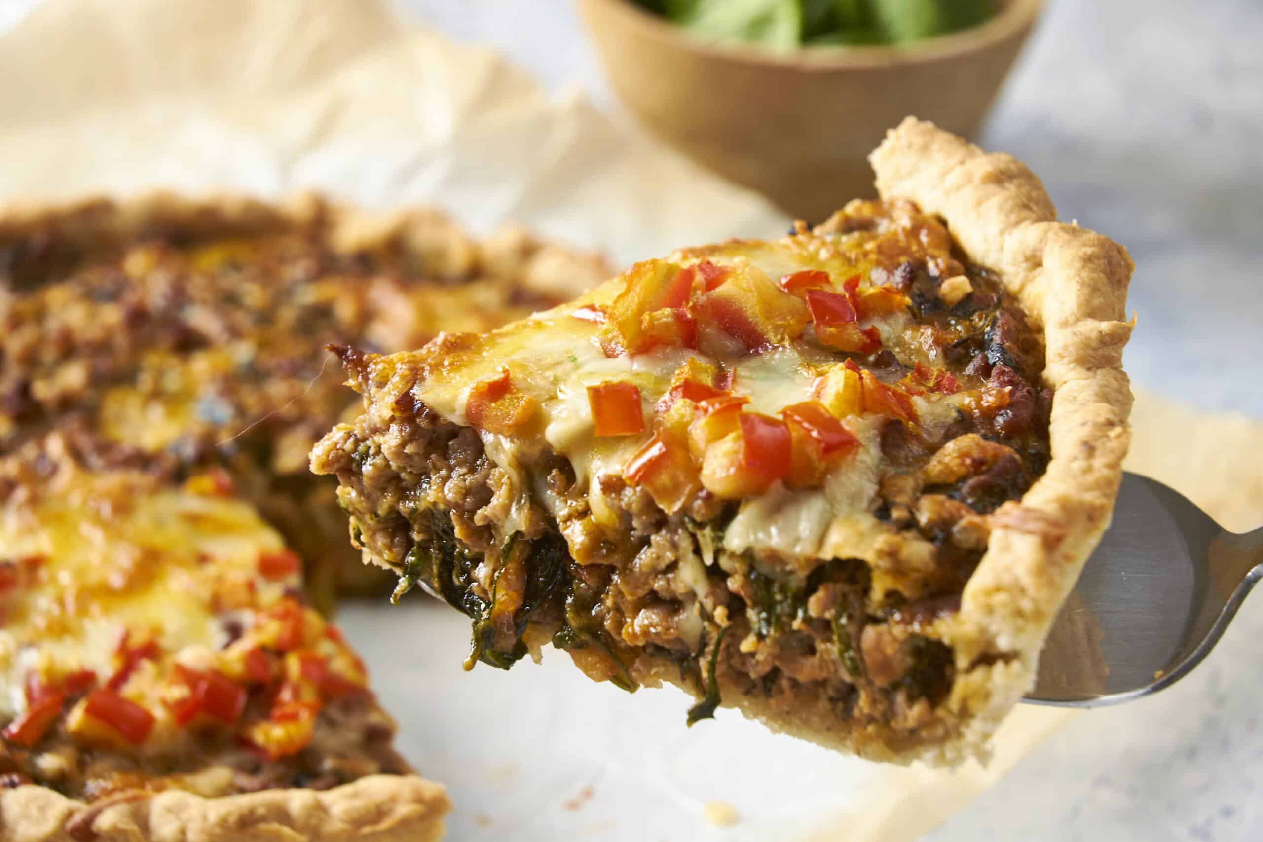 Savory homemade meat and vegetable pie with a crispy crust and melted cheese topping, perfect for family dinners or comfort food, on a rustic surface with a fork for serving.