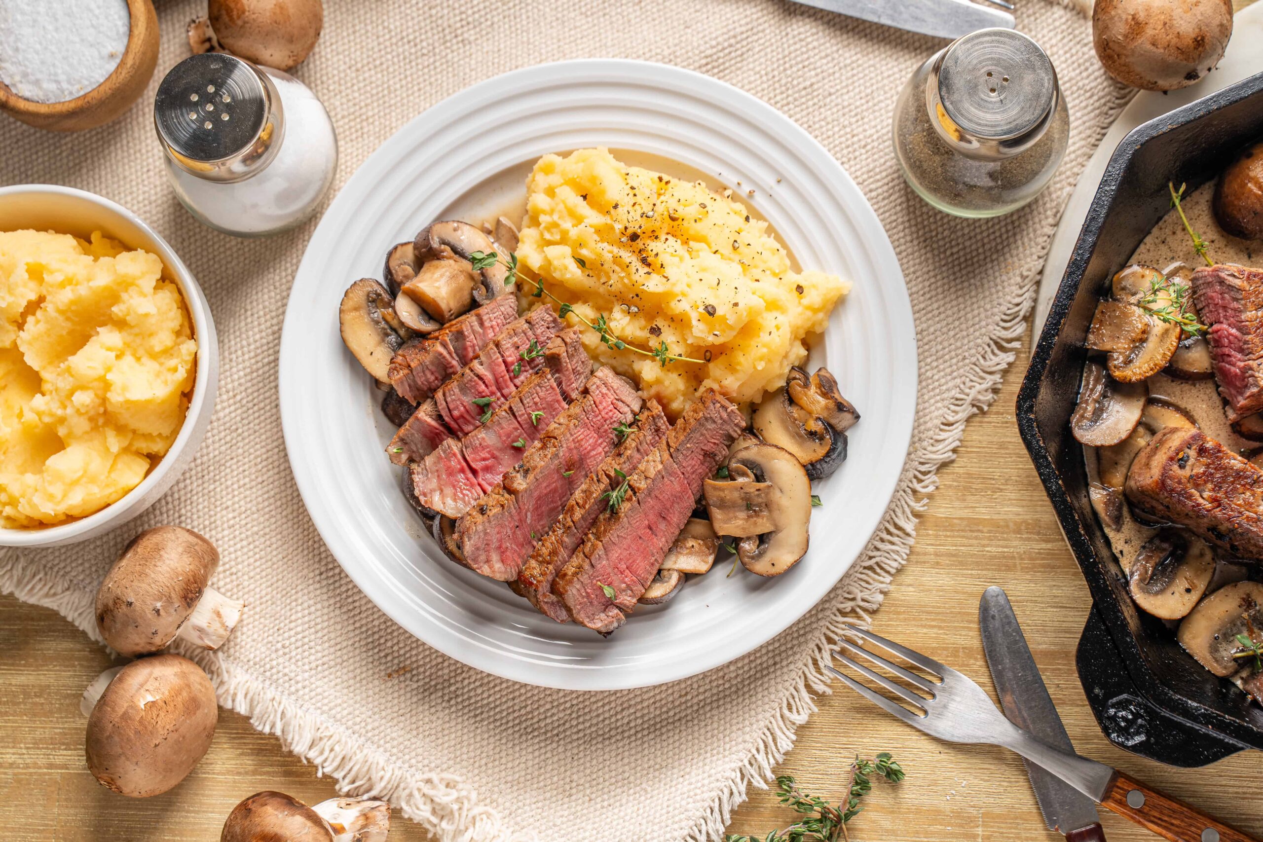 Succulent beef steak with mushroom sauce and creamy mashed potatoes served on a white plate for a hearty meal. Perfect comfort food for dinner or special occasions.