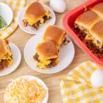 Creamy breakfast casserole with sausage, eggs, cheese, and biscuit topping on a wooden table.