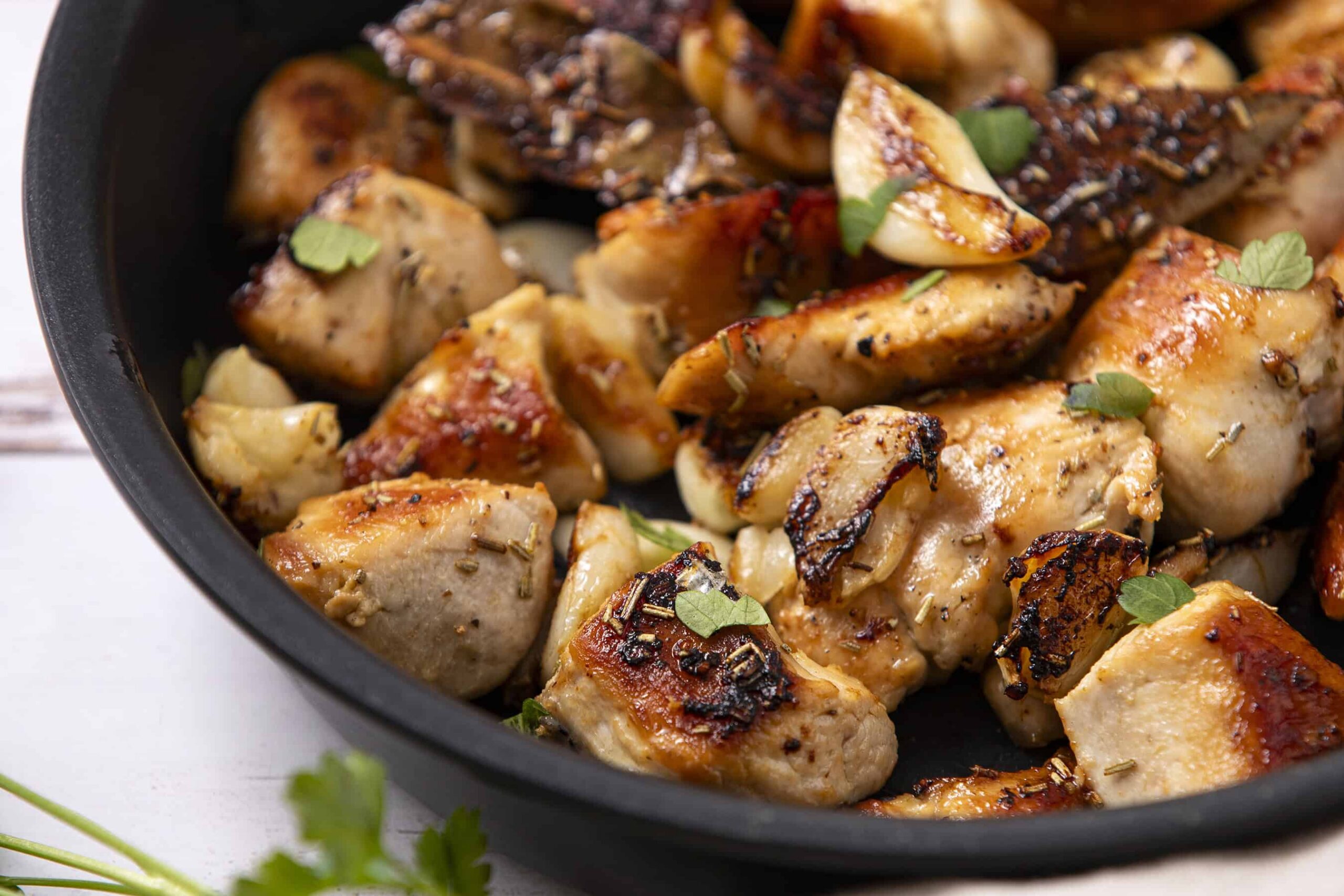 Juicy, perfectly seared chicken breast chunks garnished with fresh herbs in a skillet, showcasing a delicious and easy recipe for flavorful cooked chicken.