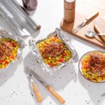 Juicy meatloaf burgers on colorful vegetable bed served in small bowls, ready to enjoy, perfect for quick and delicious family dinners, plated on a modern kitchen table.