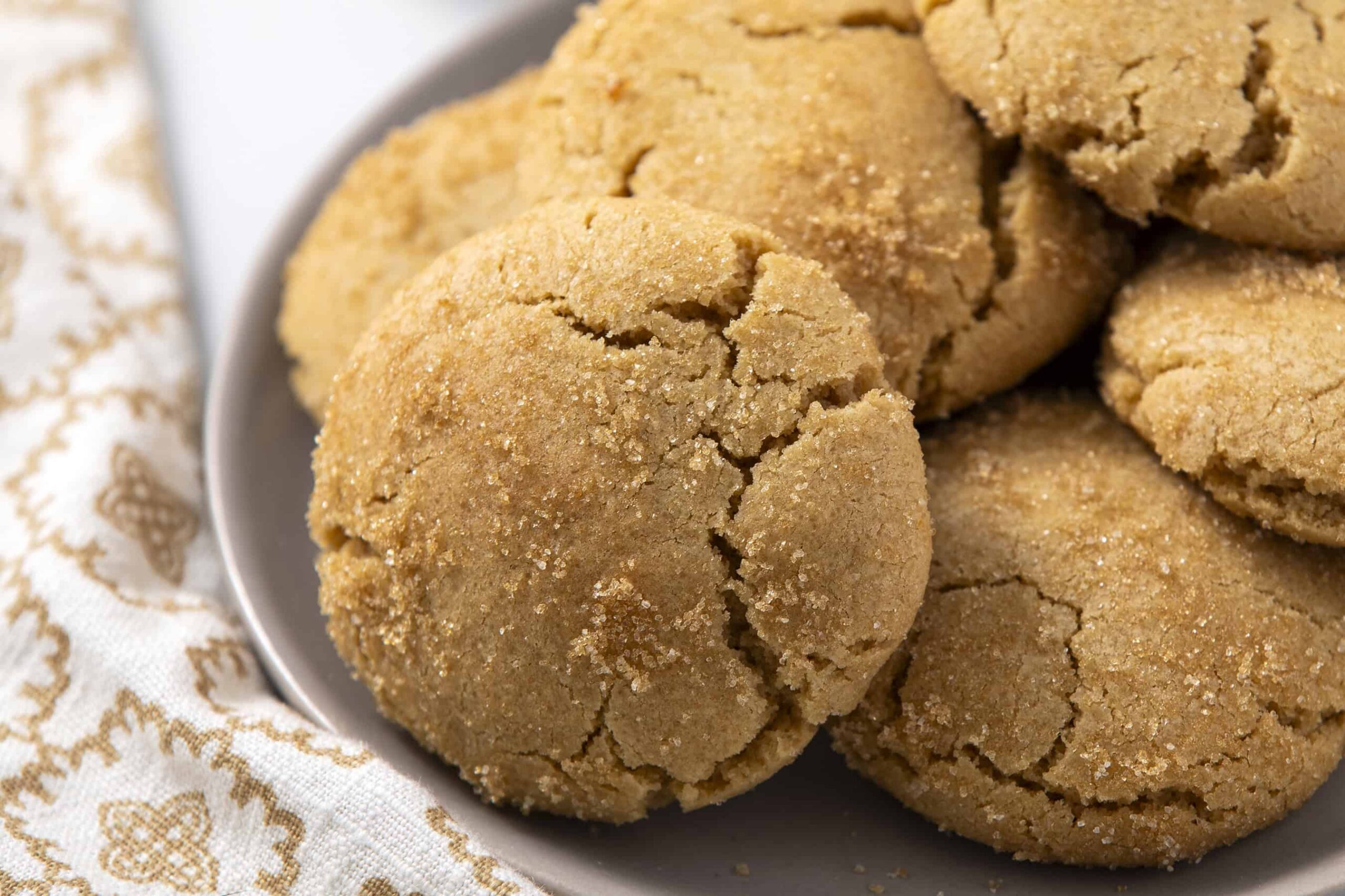 Butterscotch cookies on a white plate with a textured cloth background, showcasing the crumbly, golden-brown exterior and rich flavor. Perfect for baking and sweet treats, ideal for cookie lovers and dessert recipes.