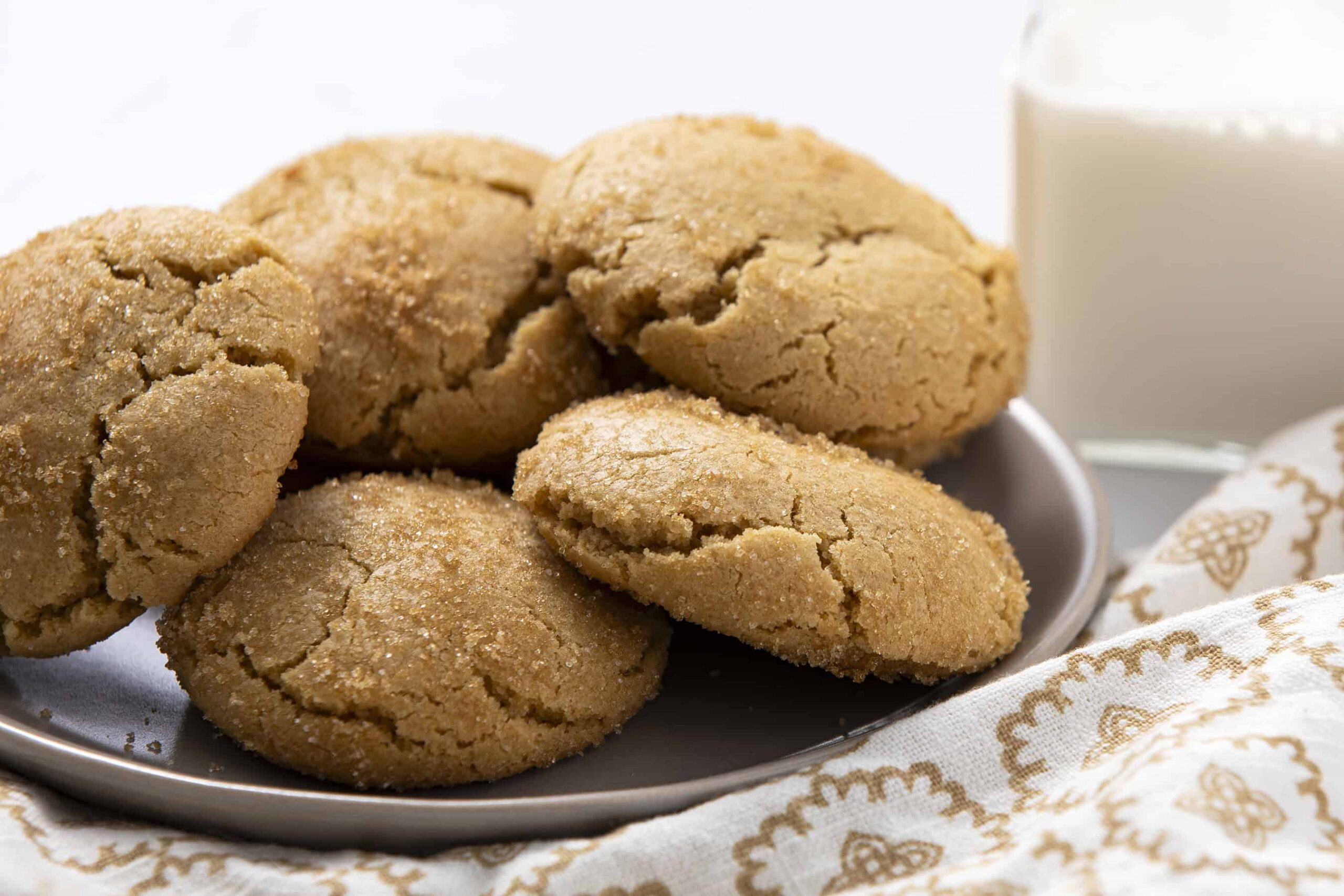 Soft, buttery peanut butter cookies on a gray plate with a glass of milk in the background, perfect for snack or dessert. Homemade cookies with a golden, crisp exterior and chewy center, ideal for peanut butter lovers.
