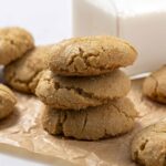 Butterscotch cookies stacked and scattered on parchment paper with a white background, showcasing their chewy texture and caramel flavor. Perfect for a sweet homemade treat or dessert recipe.