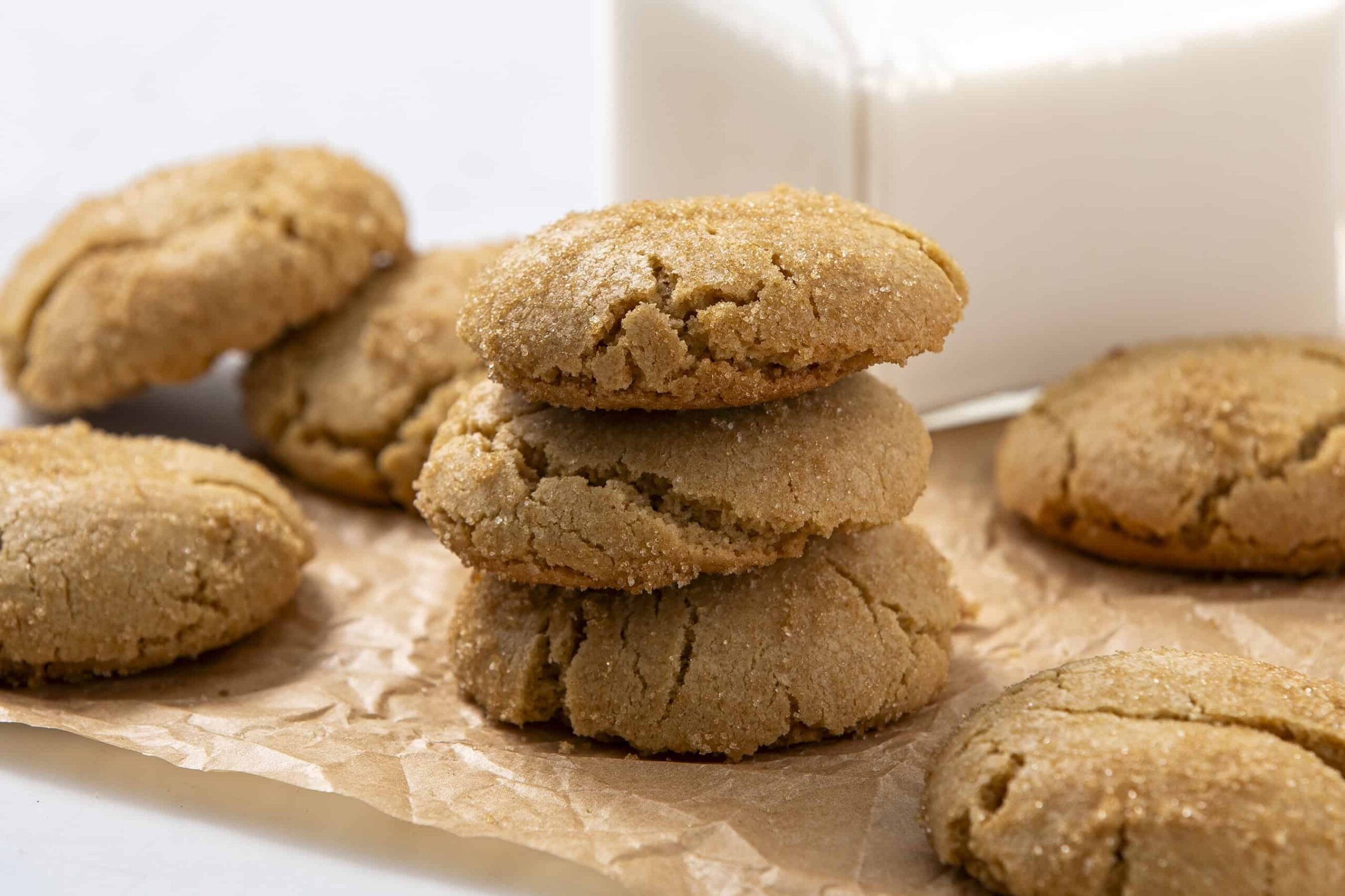 Butterscotch cookies stacked and scattered on parchment paper with a white background, showcasing their chewy texture and caramel flavor. Perfect for a sweet homemade treat or dessert recipe.