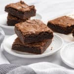 Rich, fudgy chocolate brownies on white plates with a marble background, perfect for dessert or snack, featuring classic homemade brownie recipes with melted chocolate and cocoa.