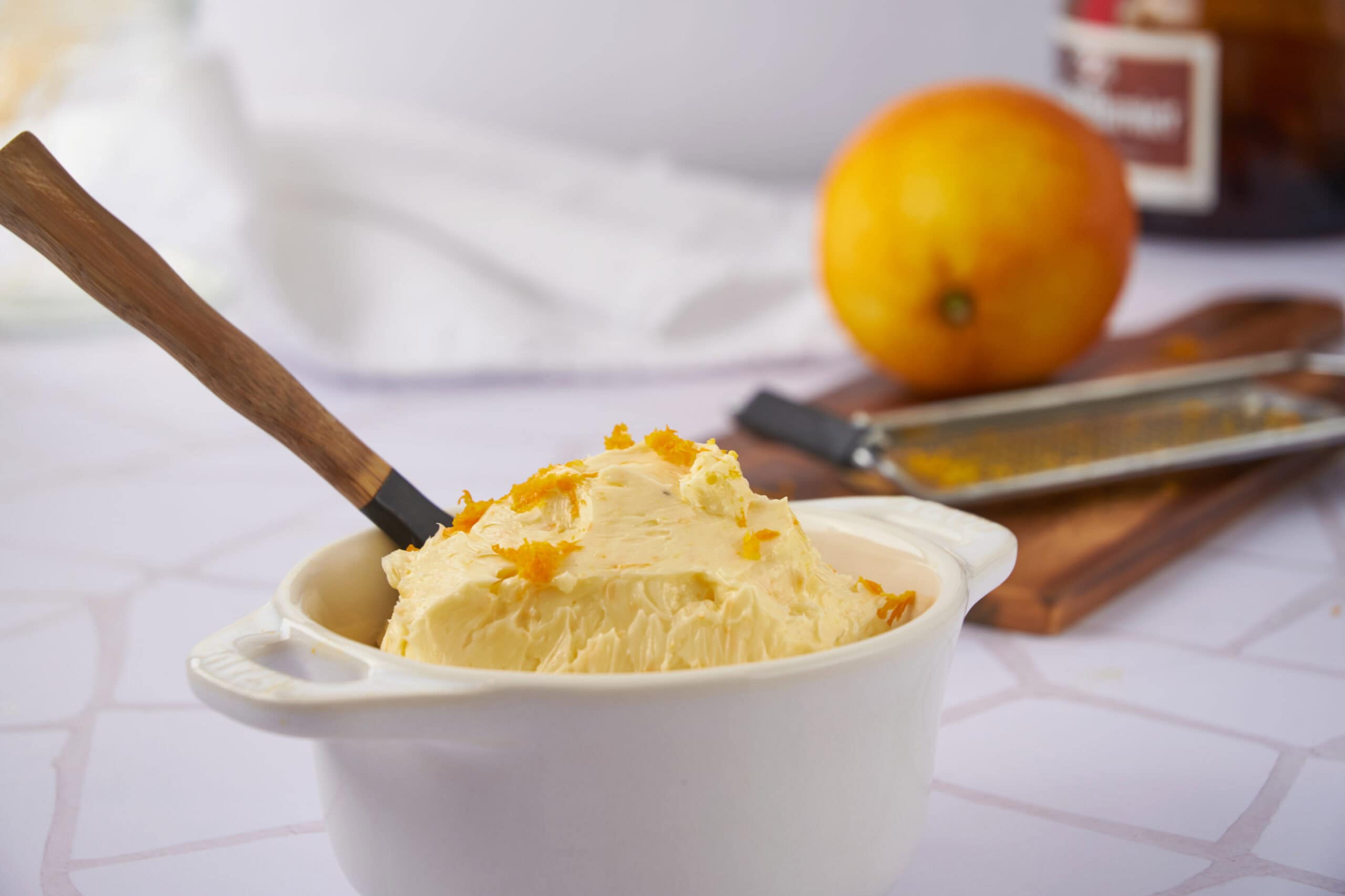Creamy homemade lemon ice cream with grated lemon zest in a white ceramic bowl on a kitchen countertop. Healthy, refreshing dessert made with fresh citrus for summer.