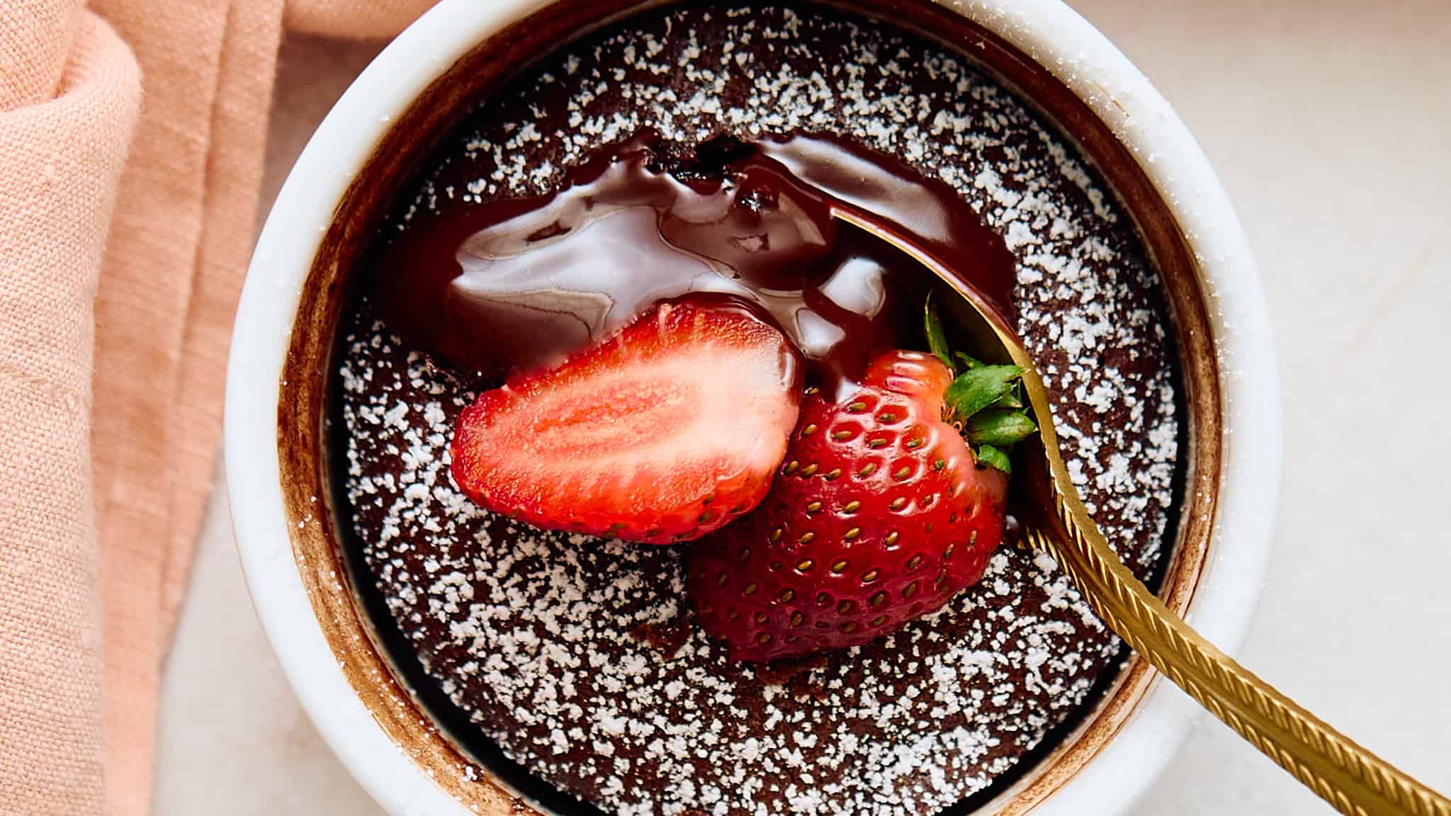 Rich molten chocolate lava cake topped with fresh strawberries and dusted with powdered sugar for a decadent dessert.
