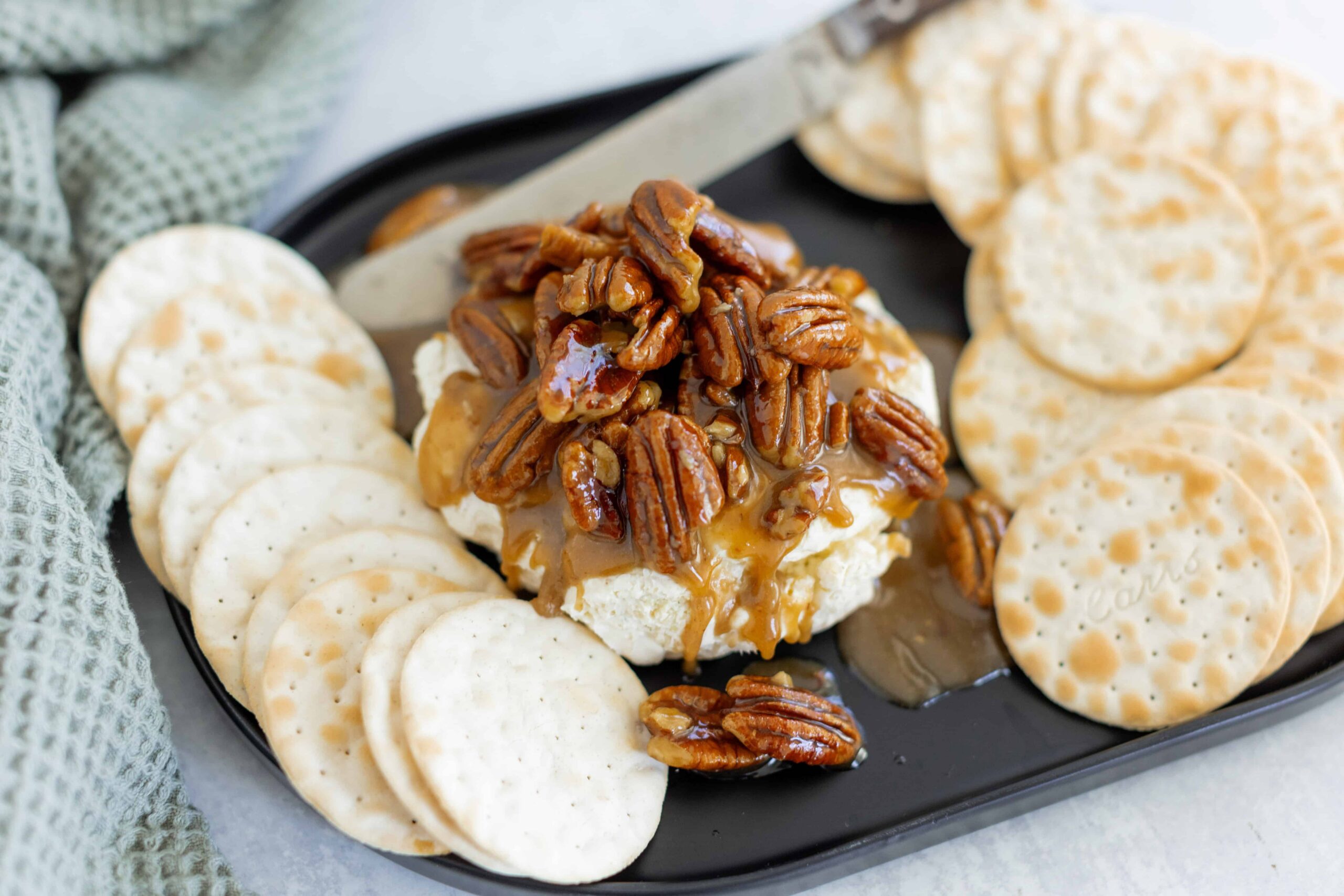 Sweet cheese ball topped with caramelized pecans served with crispy cheese crackers for a delicious snack or appetizer. Perfect for parties, brunch, or as a sweet treat.