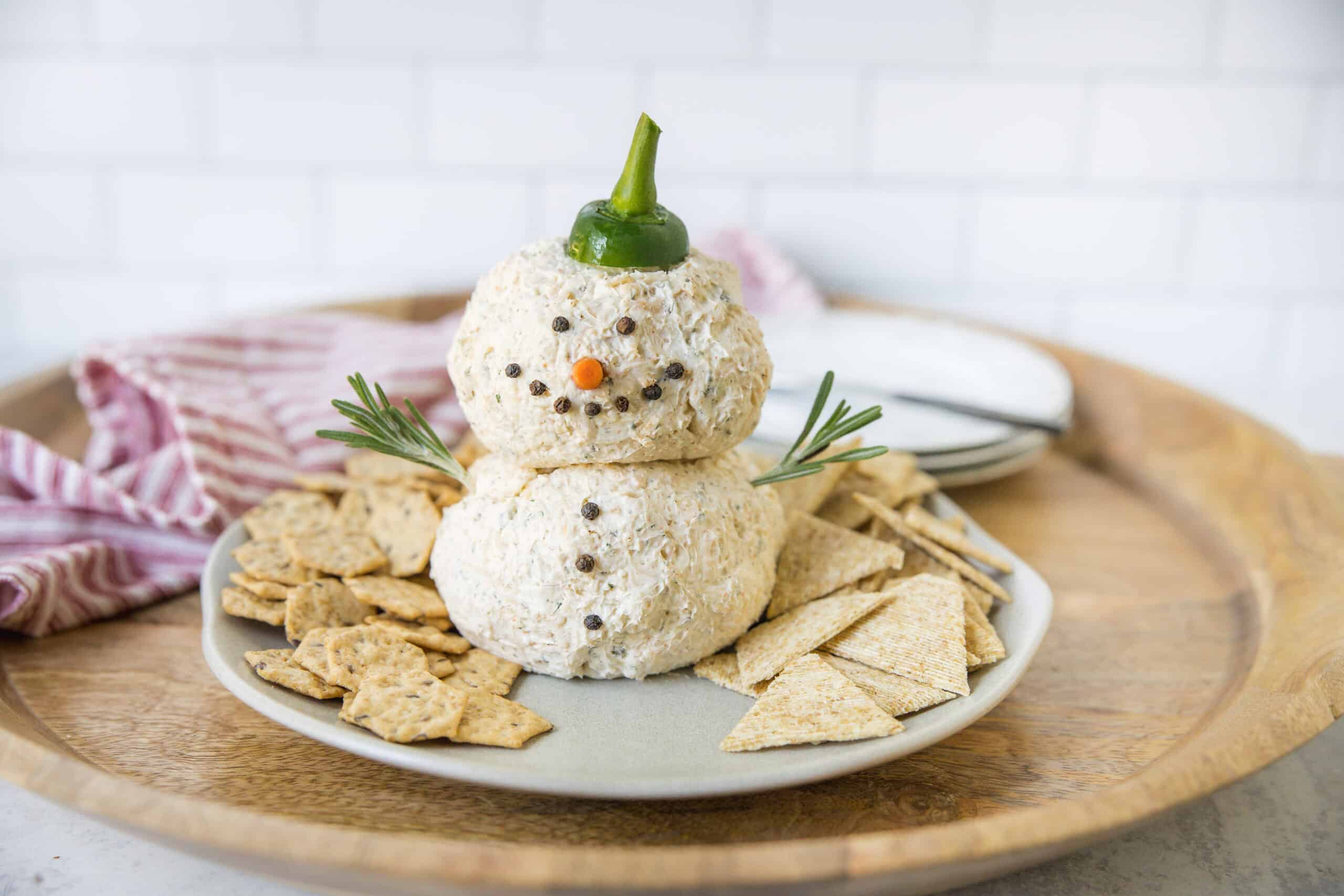 Cream cheese snowman with cracker snacks, holiday appetizer, festive Christmas appetizer, cheese ball snowman, holiday party snack, cheese ball decoration, easy holiday appetizer, cheese ball gingerbread man, Christmas party finger food, cheese appetizer with crackers.