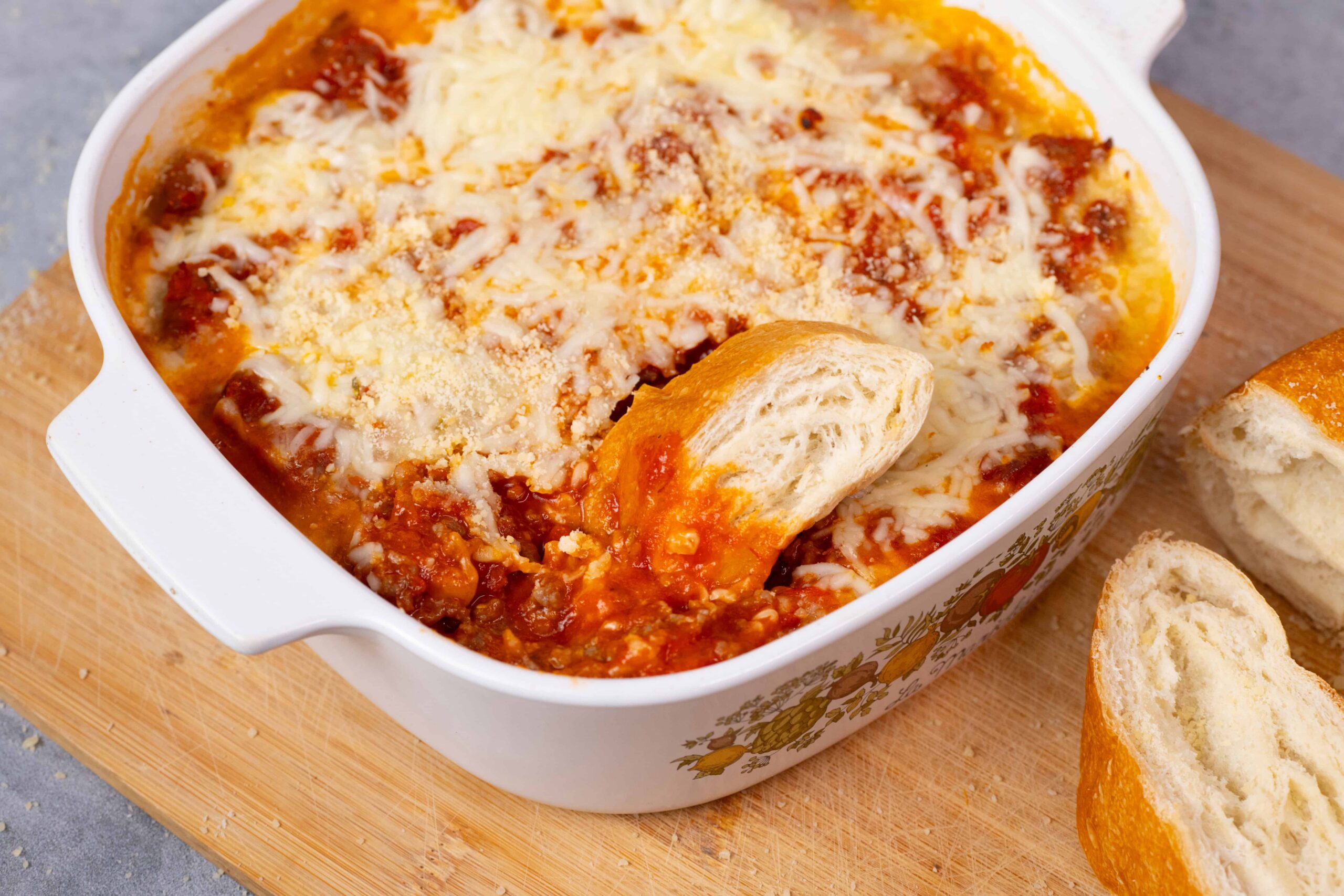 Creamy, homemade lasagna with layers of rich tomato sauce, melted cheese, and tender pasta, served in a decorative baking dish with freshly sliced bread on the side. Perfect for family dinners and comfort food lovers.