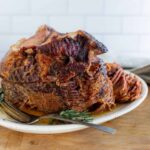 Succulent pot roast beef cooking in flavorful gravy, served on a white plate with fresh herbs and a fork. Perfect for hearty family dinners or special occasions, showcasing tender, slow-cooked meat.