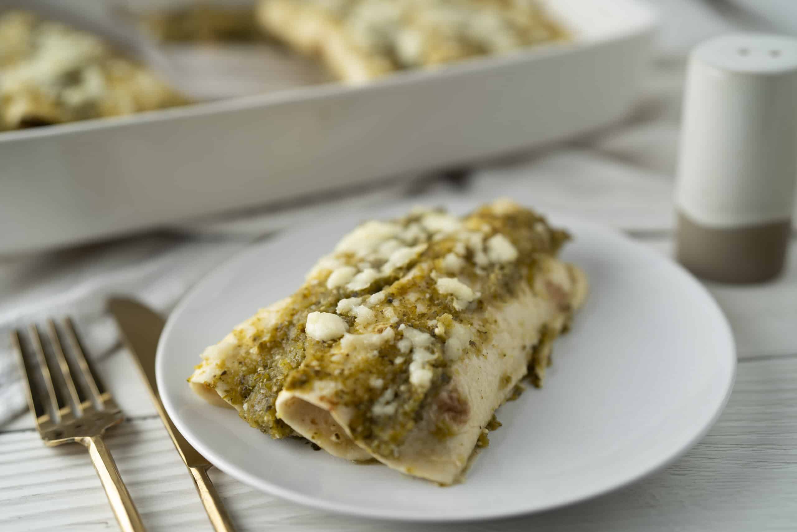 Creamy Turkey Enchiladas with Green Sauce and Crumbled Cheese, served on a white plate. Perfect comfort food for a flavorful Mexican-inspired meal.