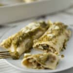 Savory chicken and mushroom enchiladas topped with creamy sauce and cheese on a white plate. Perfect for easy weeknight dinners or meal prep. Delicious, hearty, and flavorful Mexican-inspired dish.