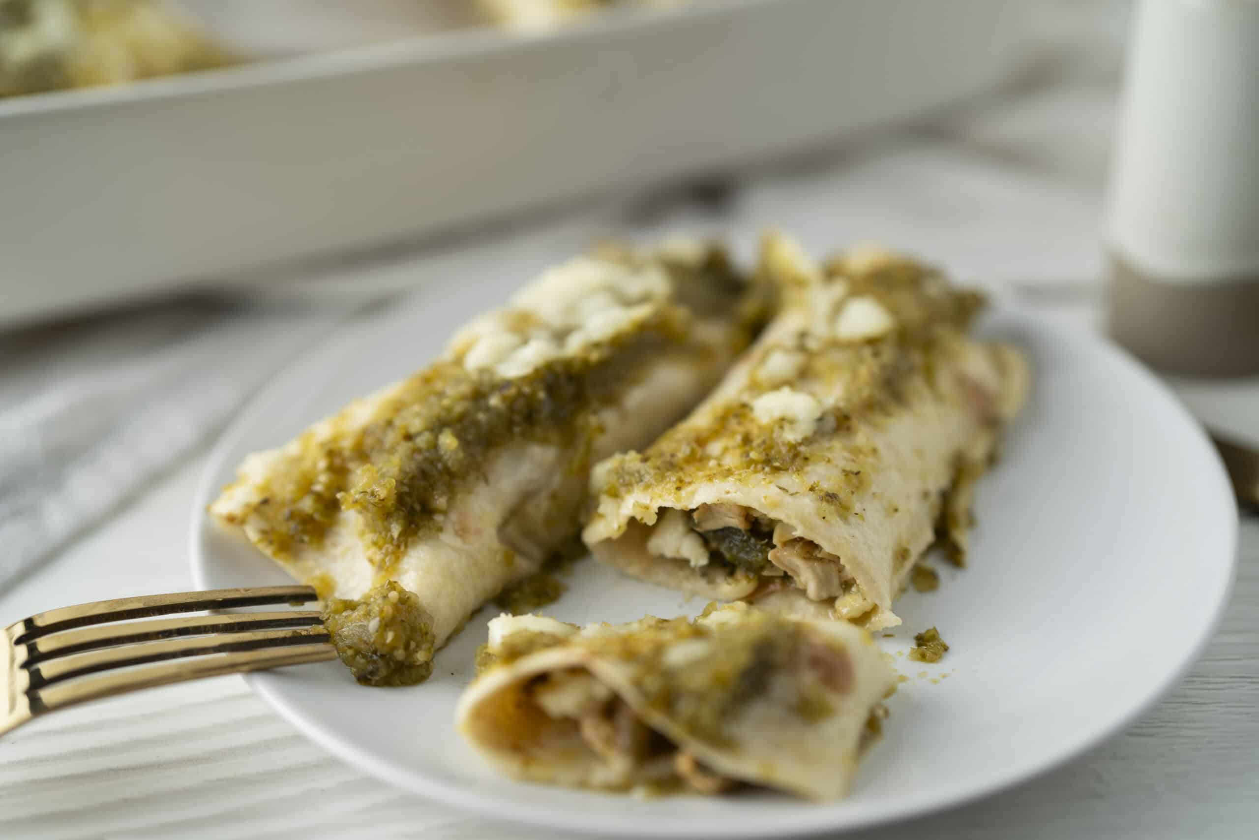 Savory chicken and mushroom enchiladas topped with creamy sauce and cheese on a white plate. Perfect for easy weeknight dinners or meal prep. Delicious, hearty, and flavorful Mexican-inspired dish.