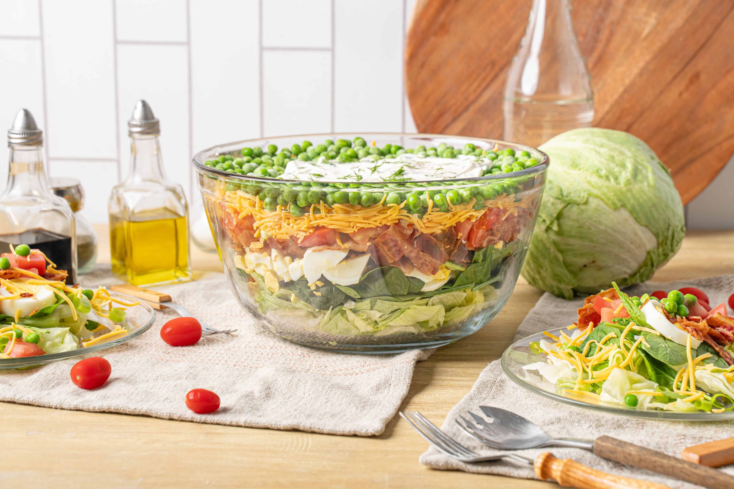 Fresh classic layers of chicken, eggs, cheese, and vegetables in a large glass bowl for a hearty chicken salad recipe. Perfect for lunch or dinner, served with fresh side salads and healthy ingredients.