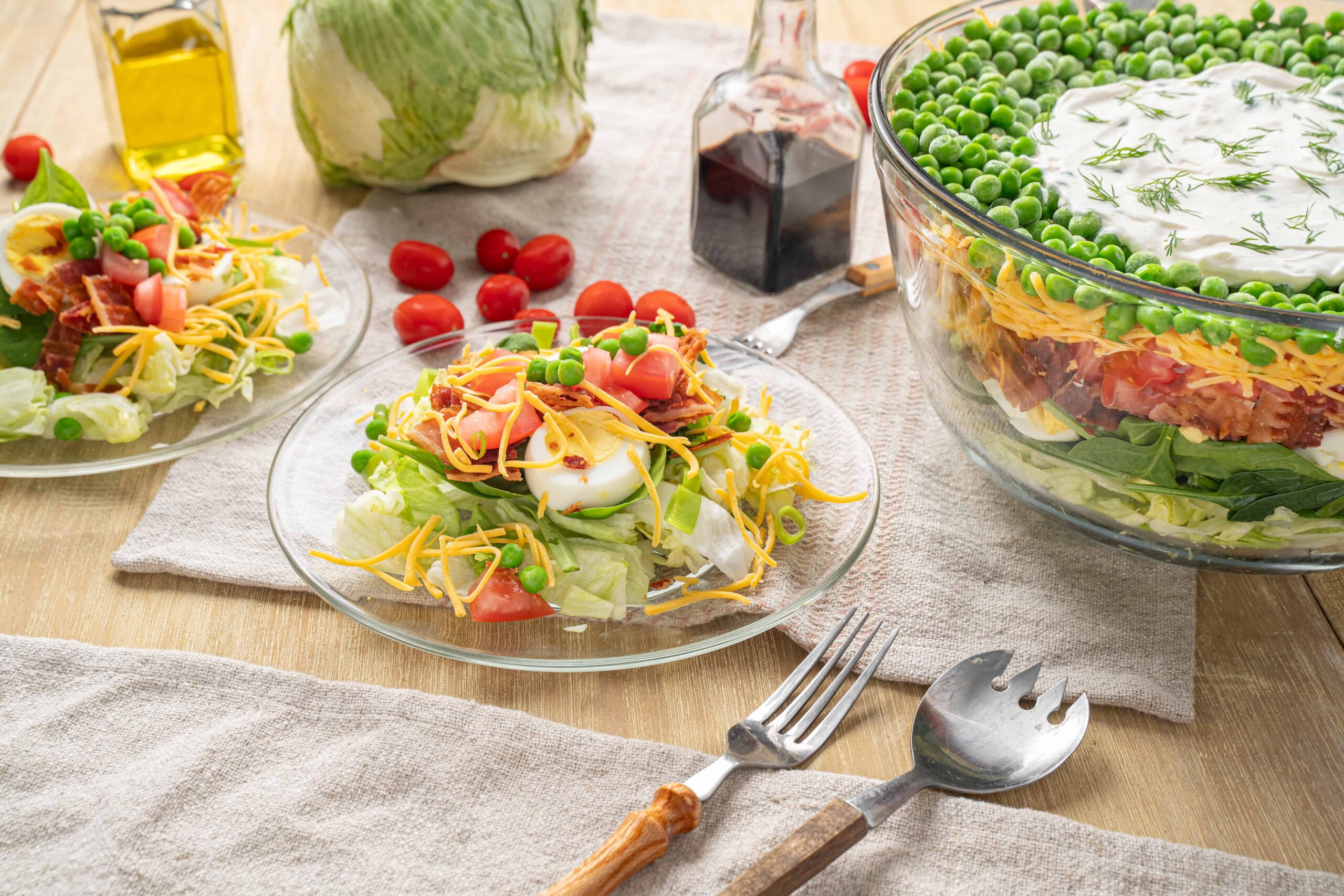 Fresh homemade chef salad with eggs, tomatoes, green peas, cheese, and lettuce served on glass plates; colorful and healthy dinner option.