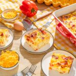 Creamy breakfast casserole with eggs, cheese, bacon, and vegetables served in a baking dish and on individual plates, perfect for brunch or family meals.