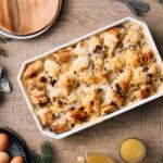 Creamy chicken and mushroom casserole with crispy pastry topped with cheese, served in a white baking dish on a rustic wooden table.