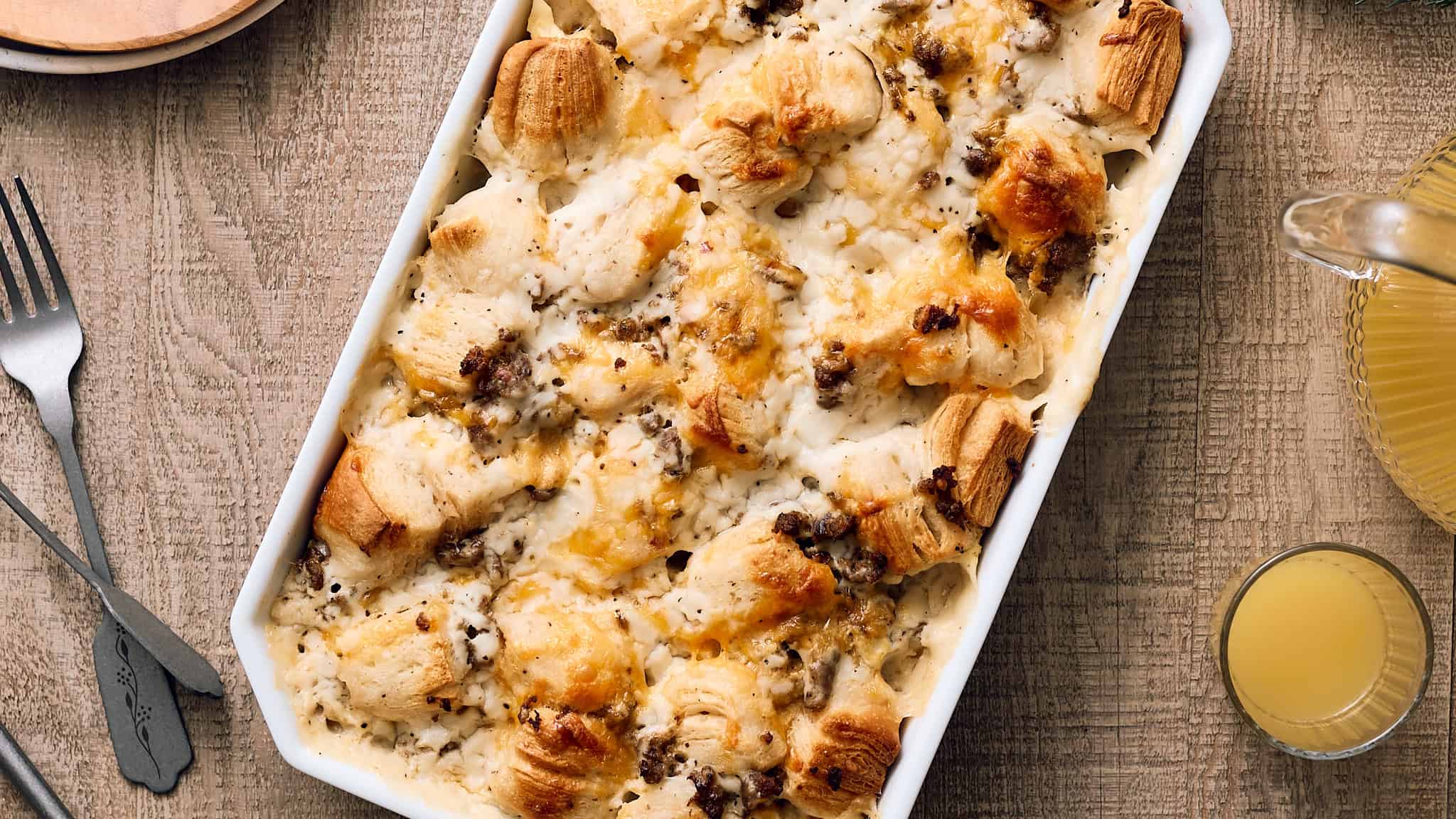 Creamy chicken and mushroom casserole baked with flaky puff pastry, topped with melted cheese, served in a white ceramic dish on rustic wooden table.
