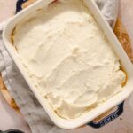 Creamy homemade mashed potatoes in a casserole dish, served as a comfort food dish or side dish, topped with butter and herbs, perfect for family dinners or holiday meals.