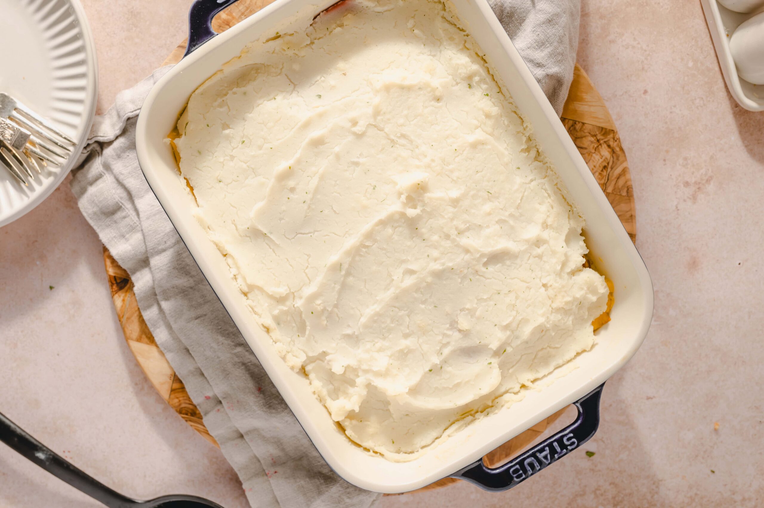 Creamy homemade mashed potatoes in a casserole dish, served as a comfort food dish or side dish, topped with butter and herbs, perfect for family dinners or holiday meals.