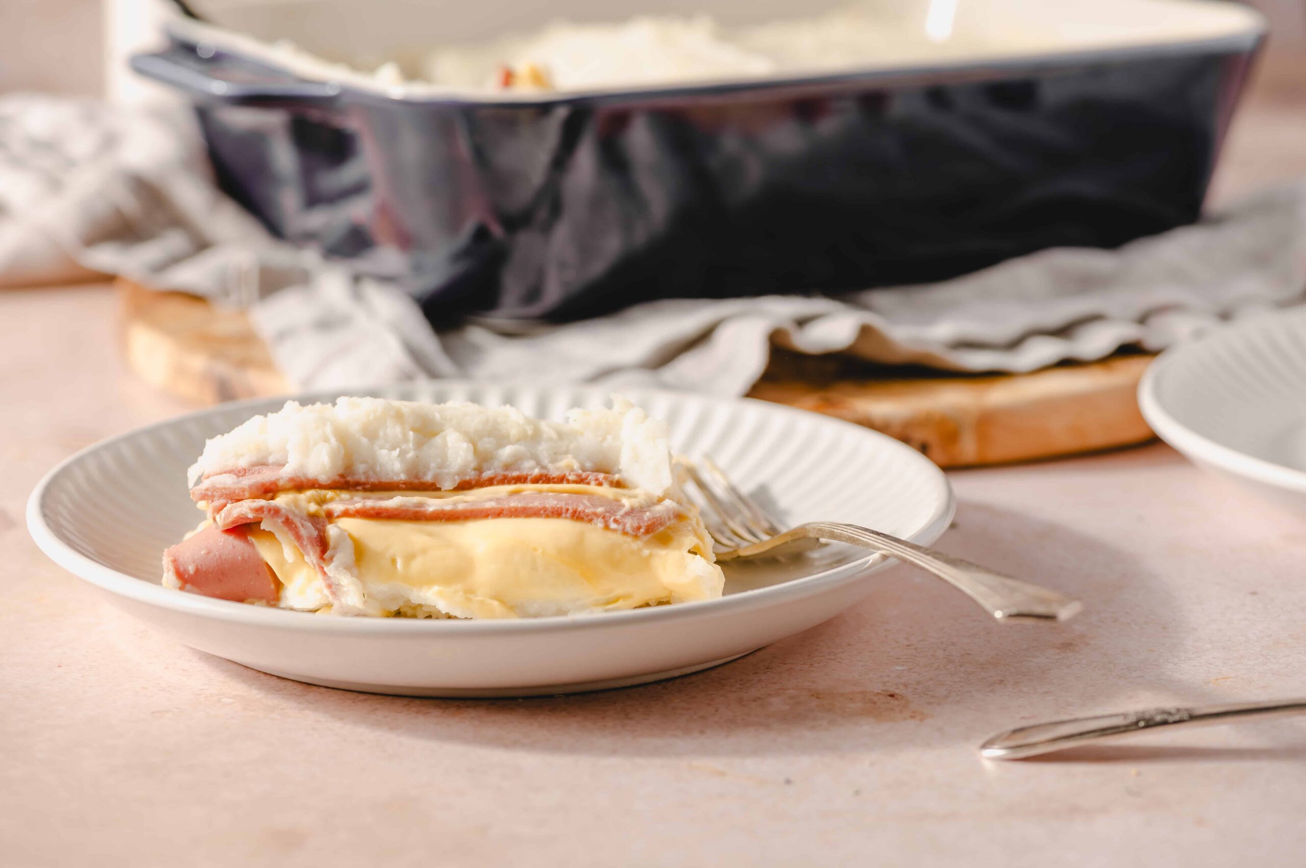 Creamy mashed potatoes layered with crispy bacon and melted cheese, served on a white plate for a delicious comfort food dish.