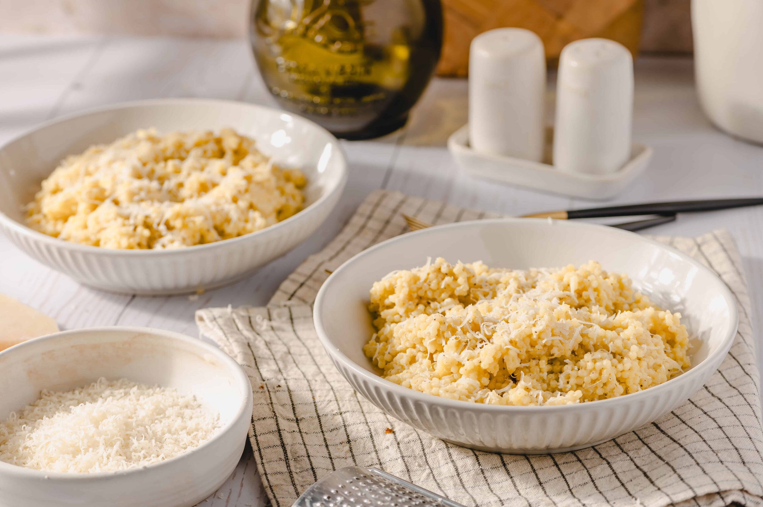 Creamy mashed potatoes with grated cheese in white bowls on a rustic kitchen table. Freshly cooked mashed potatoes topped with cheese, perfect for comfort food, side dishes, or family meals.