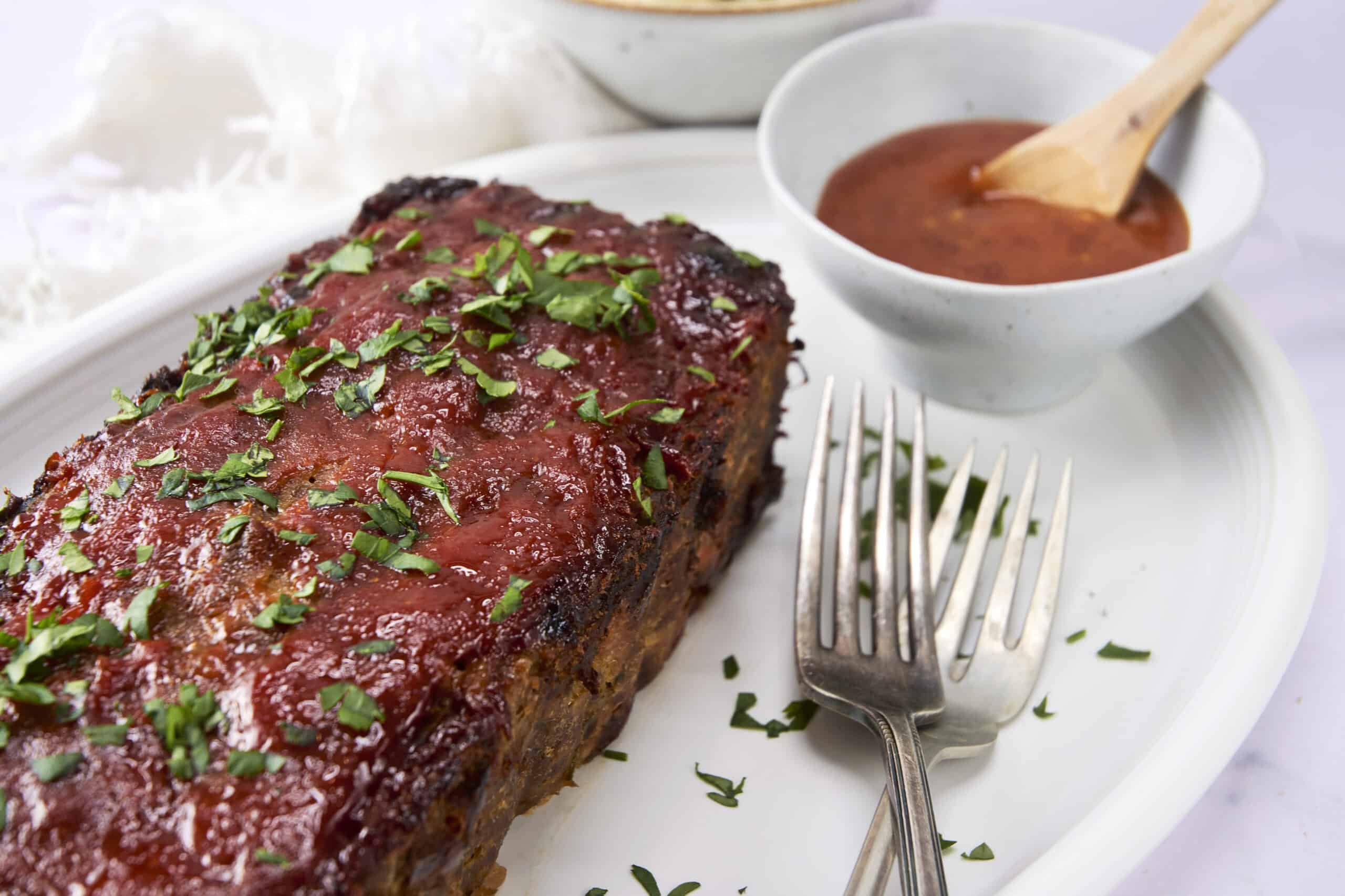 Juicy, tender BBQ ribs topped with fresh herbs served with a side of barbecue sauce and steamed rice, perfect for a flavorful and satisfying meal.