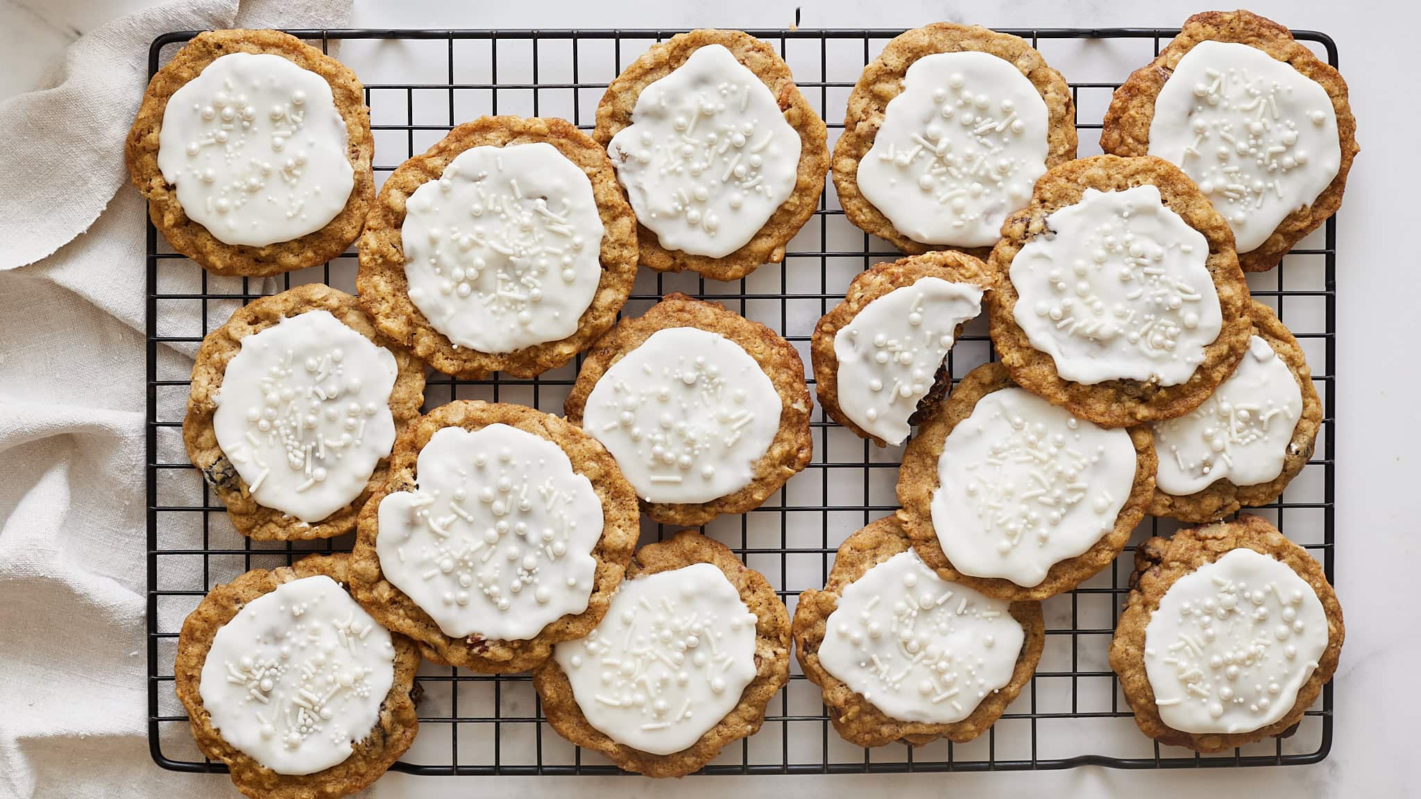 Soft oatmeal cookies topped with white icing and decorative sprinkles, perfect for holiday treats or festive occasions. Baked to golden perfection, these cookies are a delightful sweet snack.