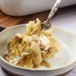 Savory beef and potato pierogi served with herbs on an off-white ceramic plate, featuring a silver fork for easy serving. Perfect comfort food, highlighting traditional Polish cuisine.