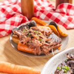Tender and flavorful slow-cooked shredded beef served with roasted carrots and potatoes, perfect for hearty family dinners and comfort food recipes.
