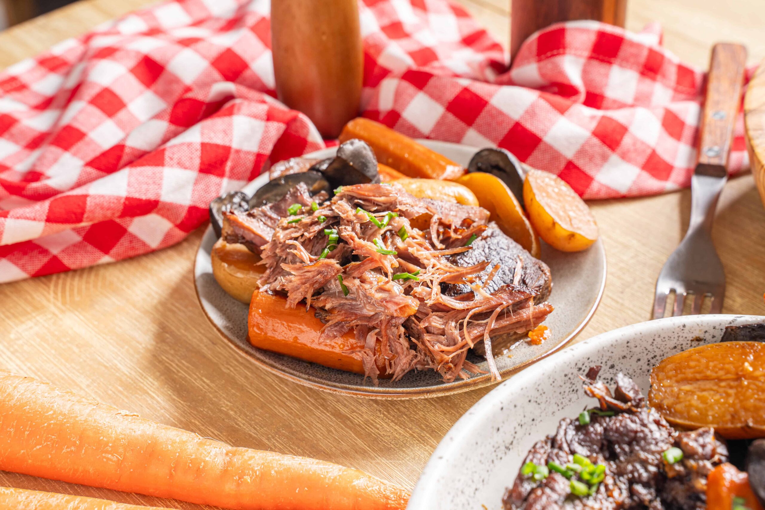 Tender and flavorful slow-cooked shredded beef served with roasted carrots and potatoes, perfect for hearty family dinners and comfort food recipes.